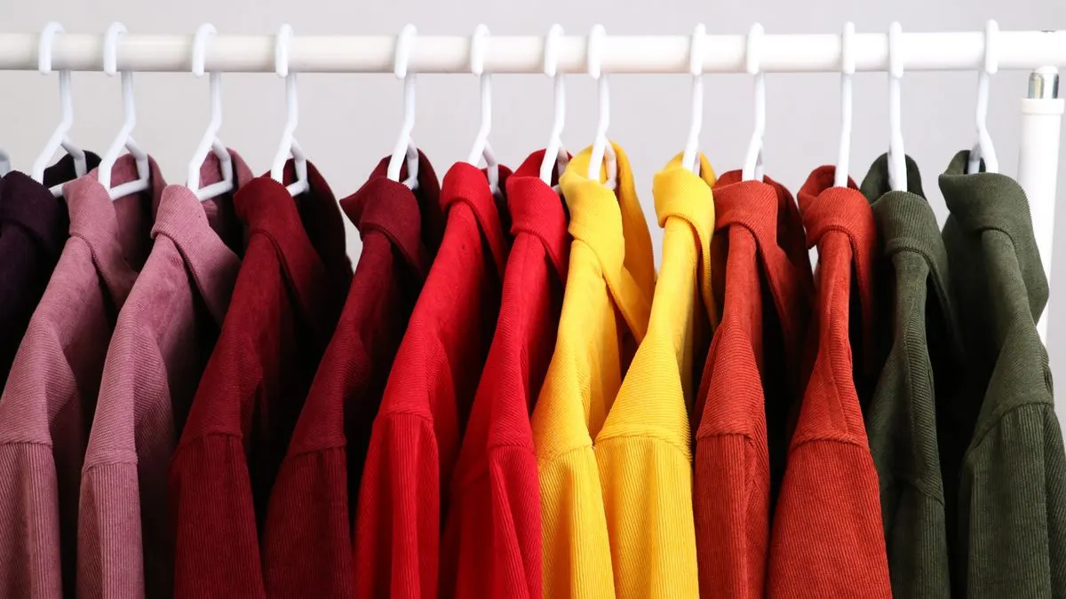 Colourful second-hand clothes arranged on a rail for sale on Vinted