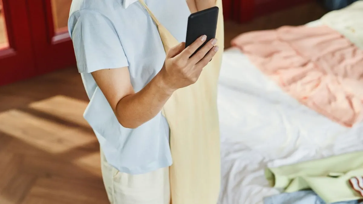 Donna con un vestito in mano che prepara un annuncio sullo smartphone